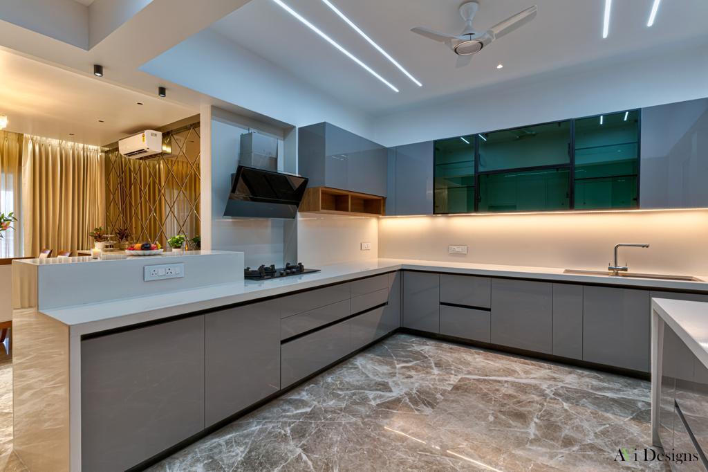 Modular kitchen and wardrobes in Aurangabad — glossy grey L-shape modular kitchen with breakfast island and glass wall units by More Than Kitchen